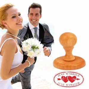 Casal de noivos com carimbo de madeira personalizado com a mensagem "Just Married"