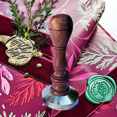 Sinete personalizado com cabo em madeira sobre lacre verde e dourado